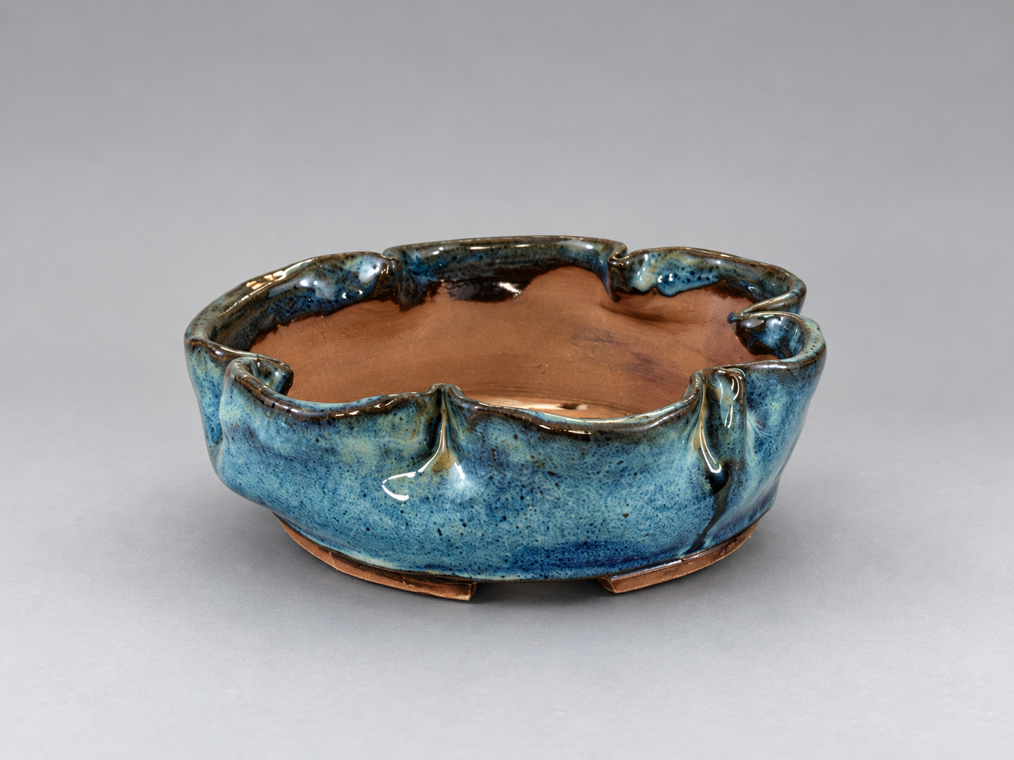 Blue-glazed shallow pot with a gently scalloped rim and small feet