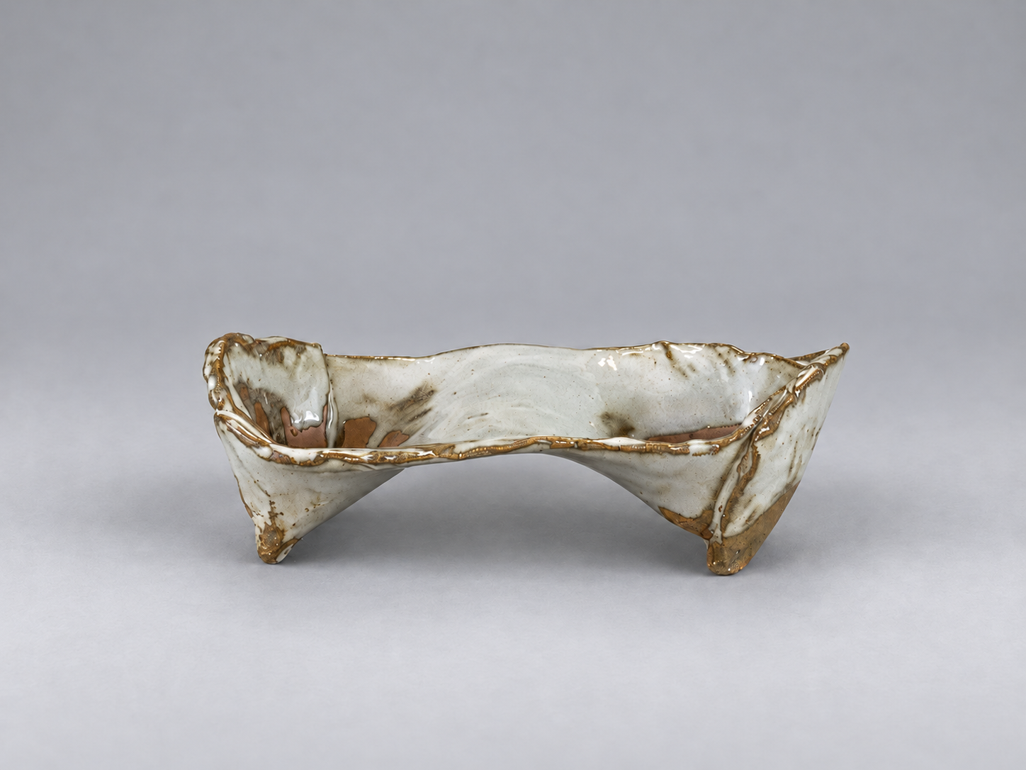Small angular cream-glazed kusamono pot with an arched underside and folded corner feet